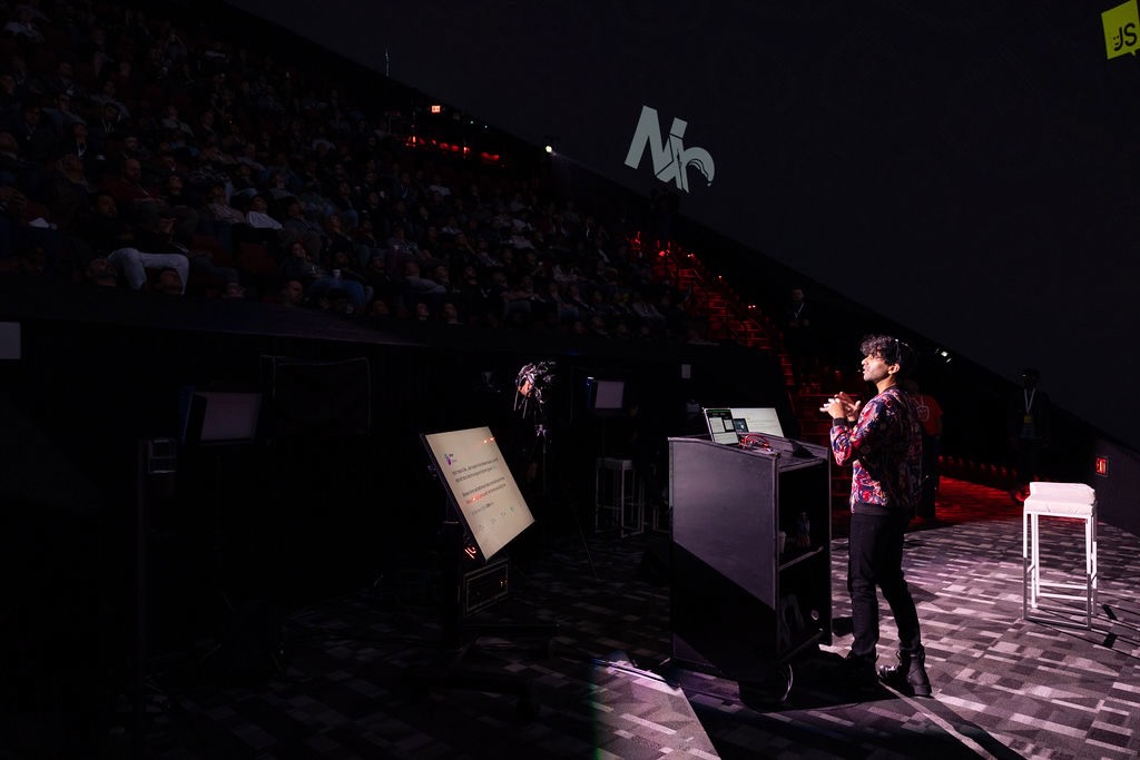 A speaker presenting on a large stage at a conference